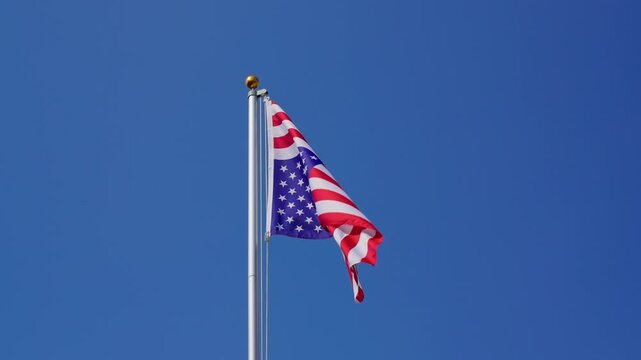 Waving USA flag flying upside down on a flagpole, slow motion, medium shot, low angle
