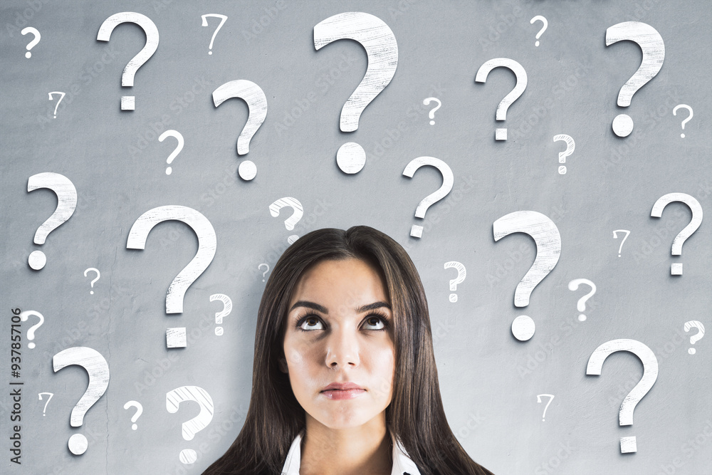Poster woman looking up at question marks on grey wall background, concept of uncertainty and problem solvi