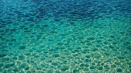 Obraz premium Close-up of clear ocean water with unique circular patterns created by sunlight reflections. The turquoise and emerald hues blend beautifully, showcasing the tranquil and pristine water surface.