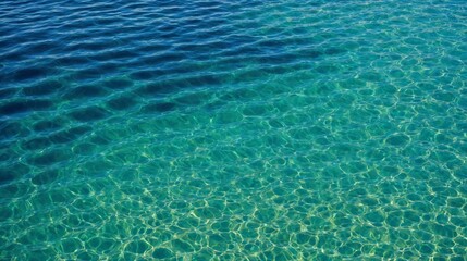 Obraz premium Close-up of clear ocean water with unique circular patterns created by sunlight reflections. The turquoise and emerald hues blend beautifully, showcasing the tranquil and pristine water surface.