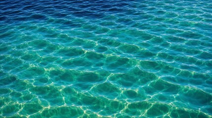 Close-up of clear ocean water with unique circular patterns created by sunlight reflections. The turquoise and emerald hues blend beautifully, showcasing the tranquil and pristine water surface.