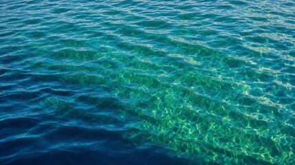 Obraz premium Close-up of clear ocean water with unique circular patterns created by sunlight reflections. The turquoise and emerald hues blend beautifully, showcasing the tranquil and pristine water surface.