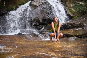 Young African Woman Sitting Near a Waterfall, Enjoying Nature