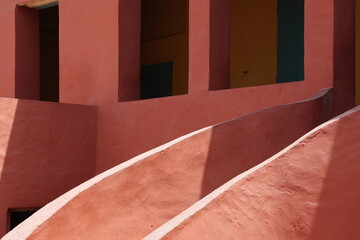 Vue d'un détail de l'escalier de couleur orangée de la maison des esclaves de l'île de Gorée au Sénégal. Rampe de forme incurvée. Architecture coloniale. Bâtiment rénové et coloré. Avril 2024.