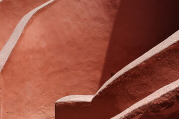 Vue d'un détail de l'escalier de couleur orangée de la maison des esclaves de l'île de Gorée au Sénégal. Rampe de forme incurvée. Architecture coloniale. Bâtiment rénové et coloré. Avril 2024.