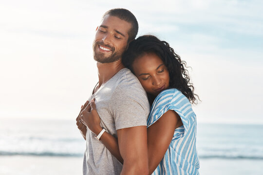 Love, couple and hug on beach for travel, smile and support in relationship. Man, woman and affection at ocean for summer vacation, holiday and commitment with milestone and engagement in California