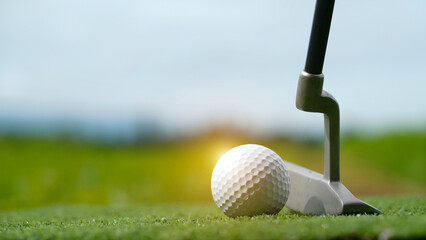 Golf clubs and balls on a green lawn in a beautiful golf course with morning sunshine.
