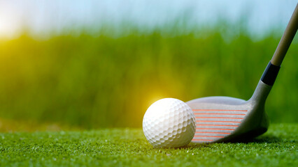 Golf clubs and balls on a green lawn in a beautiful golf course with morning sunshine.