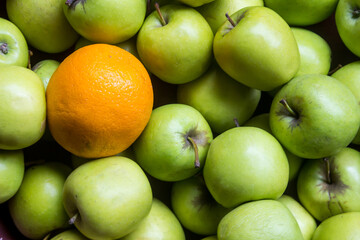 A mass of bright green apples, with a single orange