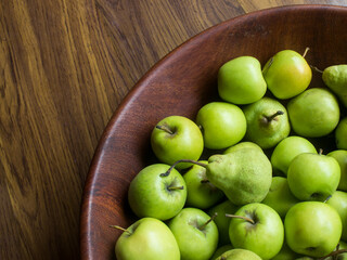 Green apples and pears in a wooden bowl