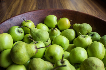 A wooden Bowl, filled with bright green Apples and Pears. Apples are some of the most widely cultivated fruit trees and there are more than 7 500 different cultivars of apples,