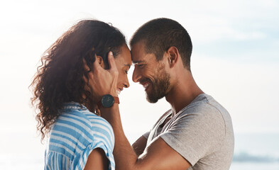 Happy, couple and forehead touch on beach for marriage romance, loyalty together and bonding with love. Smile, man and woman with relationship support, vacation anniversary and ocean for date outdoor