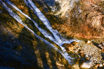 In the shadow, the stream of the waterfall flows along the steep rocks. Natural landscape. Long exposure