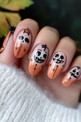 This artistic nail design showcases a blend of orange and black with playful skulls and pumpkins, perfect for Halloween celebrations.