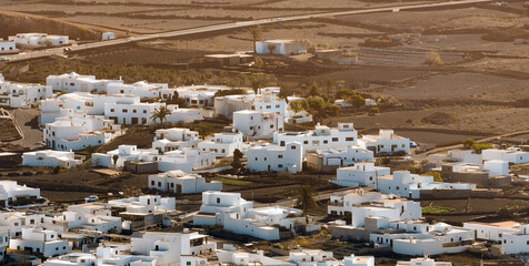White buildings, town among volcanic black mountains and lava formations in Lanzarote, Canary Islands.