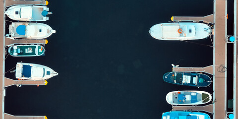 Fishing boats, yachts on a dark background, drone view from above on a bay with white motor boats. © Zhanna