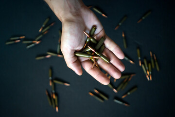 Male hands hold a handful of cartridges for weapons, close-up view.