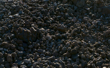 Black volcanic desert land with basalt lava formations and stones, a dark soil of the volcano.