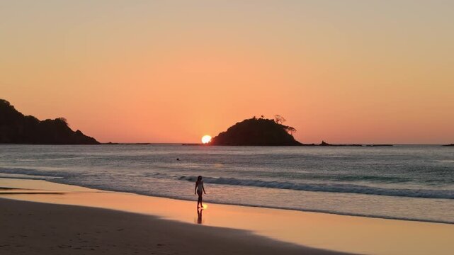 Aerial panoramic view of woman walking on a tropical beach island when sun goes down. Travel video of tourist woman relaxing in vacation in Nacpan beach Philippines 