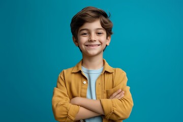 Happy boy crossing arms with a smile, isolated on blue background in cheerful pose