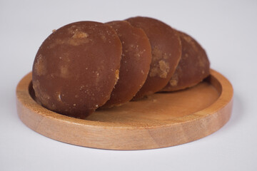 Close up of palm brown sugar on a wooden plate. Palm sugar in half-ball shape.