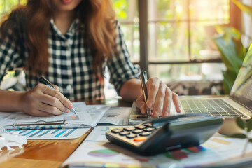 Fototapeta premium Accountant reviewing finances, calculator and documents on desk, small office setting.