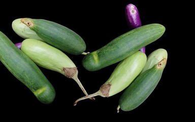 Cucumber and green eggplant vegetables on a black background are good for food.