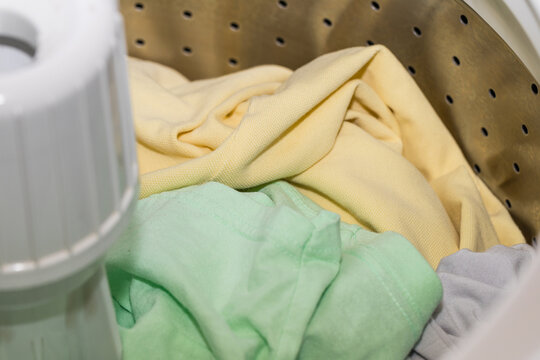 Top loading washing machine with agitator filled with clothes - selective focus