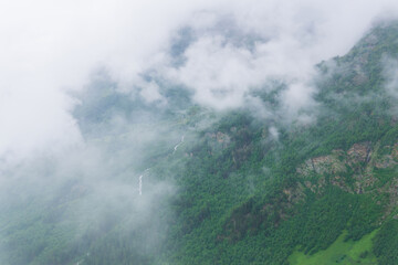 aerial view of wild forested mountain slope through clouds