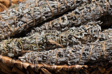 Bundles of sage neatly arranged in a basket, ready for smudging or use as spices. The image highlights the natural and aromatic qualities of sage in a rustic setting.