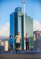 City, road and people running together for fitness, training or commitment to healthy body. Morning, exercise and group of friends on street for urban workout, outdoor challenge or sports performance