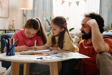 Naklejka premium Parent sitting at table with two kids engaging in drawing and coloring activities in cozy living room decorated with plants and lights, baskets and shelves in background