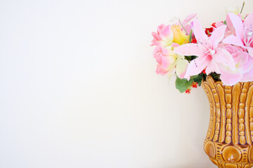 Horizontal background with space for copy showcasing a vase with pink plastic scenic flowers on the right hand side.