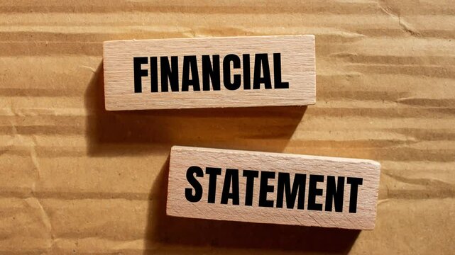 Financial statement message writing on wooden blocks on cardboard background. Conceptual financial statement symbol.