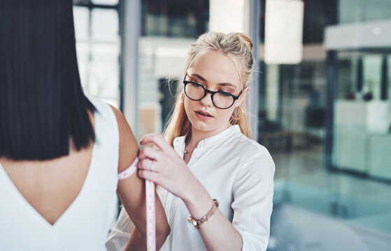 Woman, fashion designer and arm with measuring tape for size at workshop or boutique store. Young, female person or tailor checking measurement on model or body for clothing line, style or production