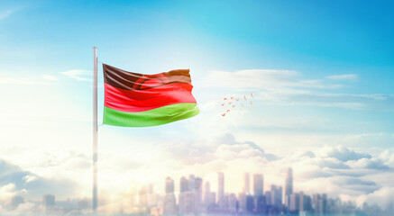 Malawi flag wavering in beautiful clouds with building skyline. The flag with drone shot in beautiful sky. Malawi national flag for independence day.