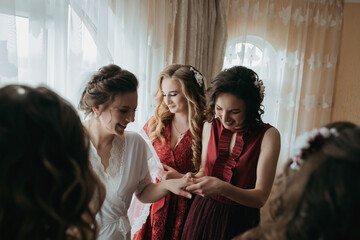 A group of women are standing together, one of them wearing a red dress. They are all smiling and seem to be enjoying each other's company