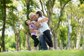 Fototapeta premium Happy Asian family children having fun and kissing her grandfather on the cheek in the park