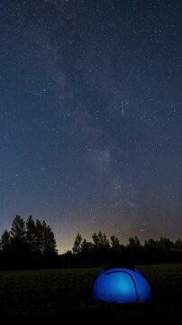 Time Lapse of Milky Way Moving over blue Glowing Tent. Night Starry Sky 