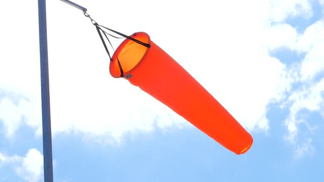 Orange wind sock indicator, blue sky and clouds