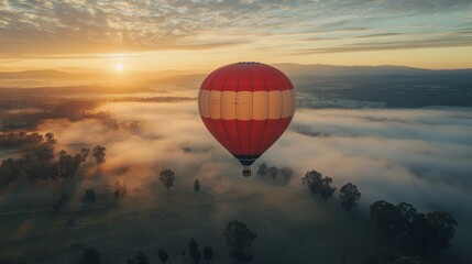 Obraz premium Hot air balloon floating over misty hills during sunrise