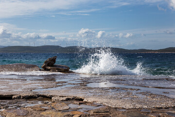 Splashing waves blue cloudy sky and aegean sea in a sunny windy day, nature's symphony