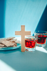 Cross and christian communion with wine and bread on blue background, vertical religion card