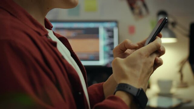 A young American student is deeply immersed in the virtual space in his home office. The IT specialist creates a digital architecture using his intelligence. He uses a modern smartphone