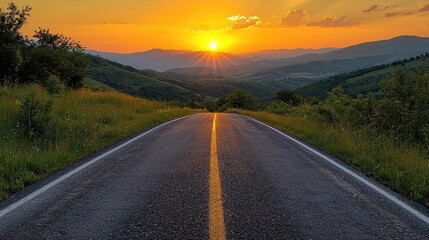 Naklejka premium Open road stretching into the distance with a vibrant orange sunset over the mountains