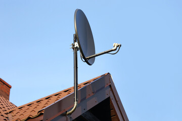 Tile roof antenna background. TV satelite dish old house roof. Countryside village architecture rooftop satelite. Television antenna mount. Red tiled roof home with mounted satellite.
