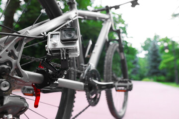 Fototapeta premium Modern action camera with mount on bicycle outdoors, closeup. Space for text