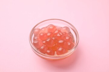 Bright tapioca pearls in bowl on pink background, closeup