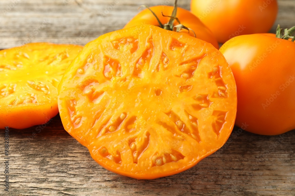 Wall mural cut and whole ripe yellow tomatoes on wooden table, closeup