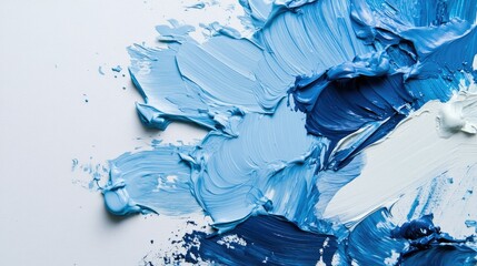 Fototapeta premium Flat lay of various shades of blue paint, mixed and spread across a white surface, viewed from the top.